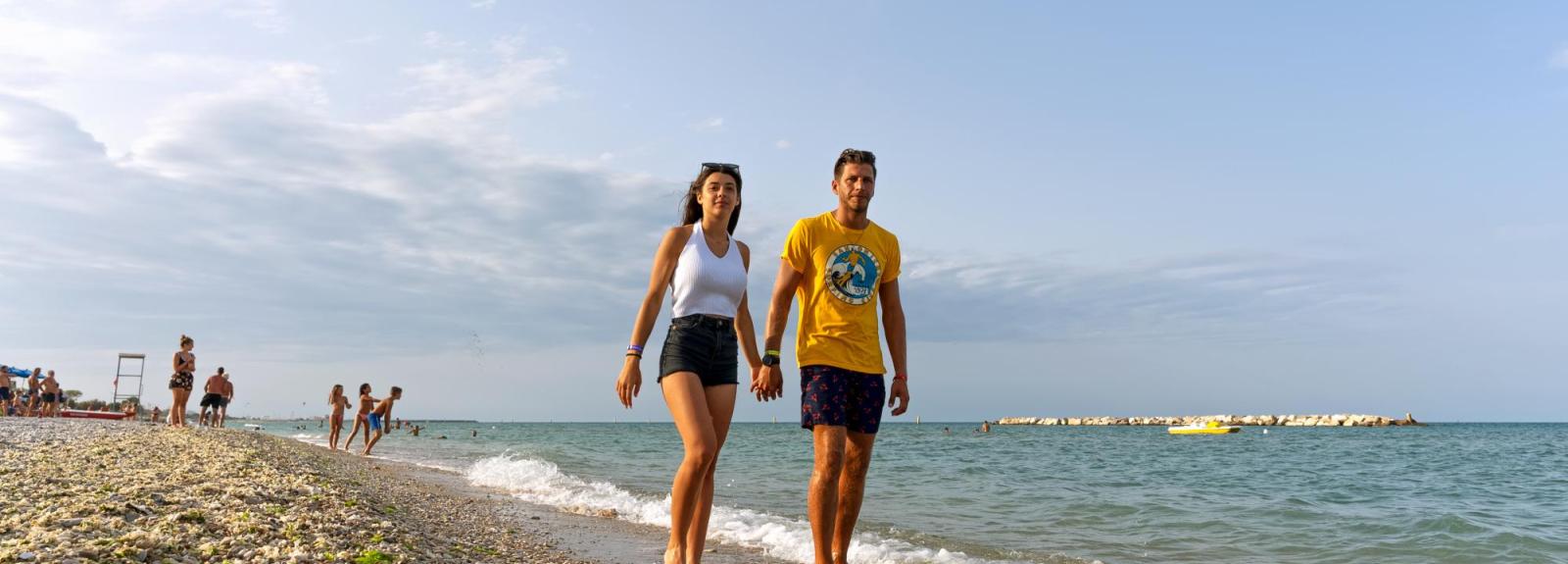Coppia cammina sulla spiaggia al tramonto.
