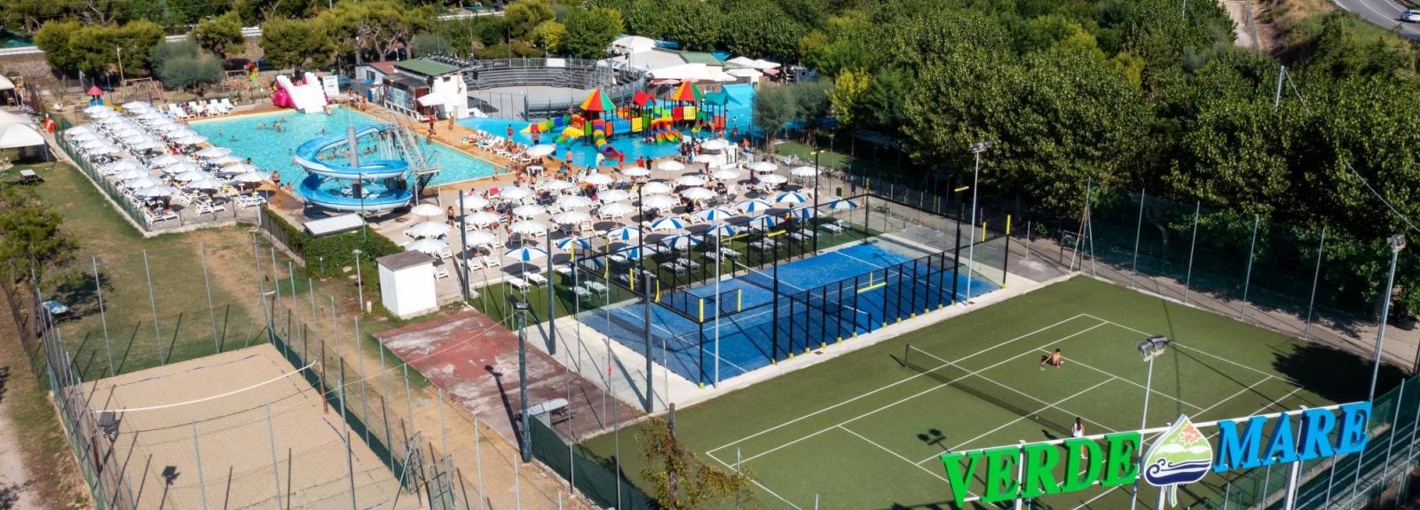 Complesso turistico con piscine, campi sportivi e vista mare.