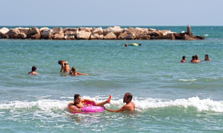 Menschen genießen das Meer mit Schwimmringen nahe einer Felsbarriere.