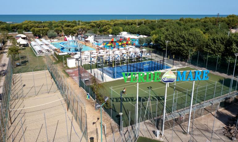 Complesso turistico con campi sportivi e piscina vicino al mare.