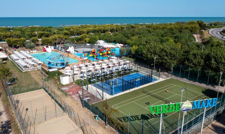 Complesso turistico con piscine, campi sportivi e vista mare.