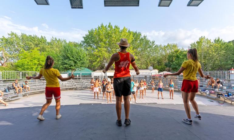 Animatori energici guidano un gruppo di persone in un ballo all'aperto.