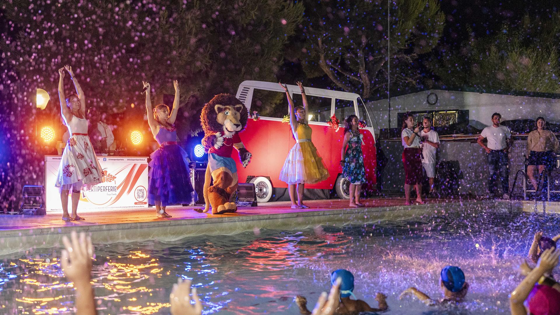 Spettacolo serale con danza e costumi vicino alla piscina.