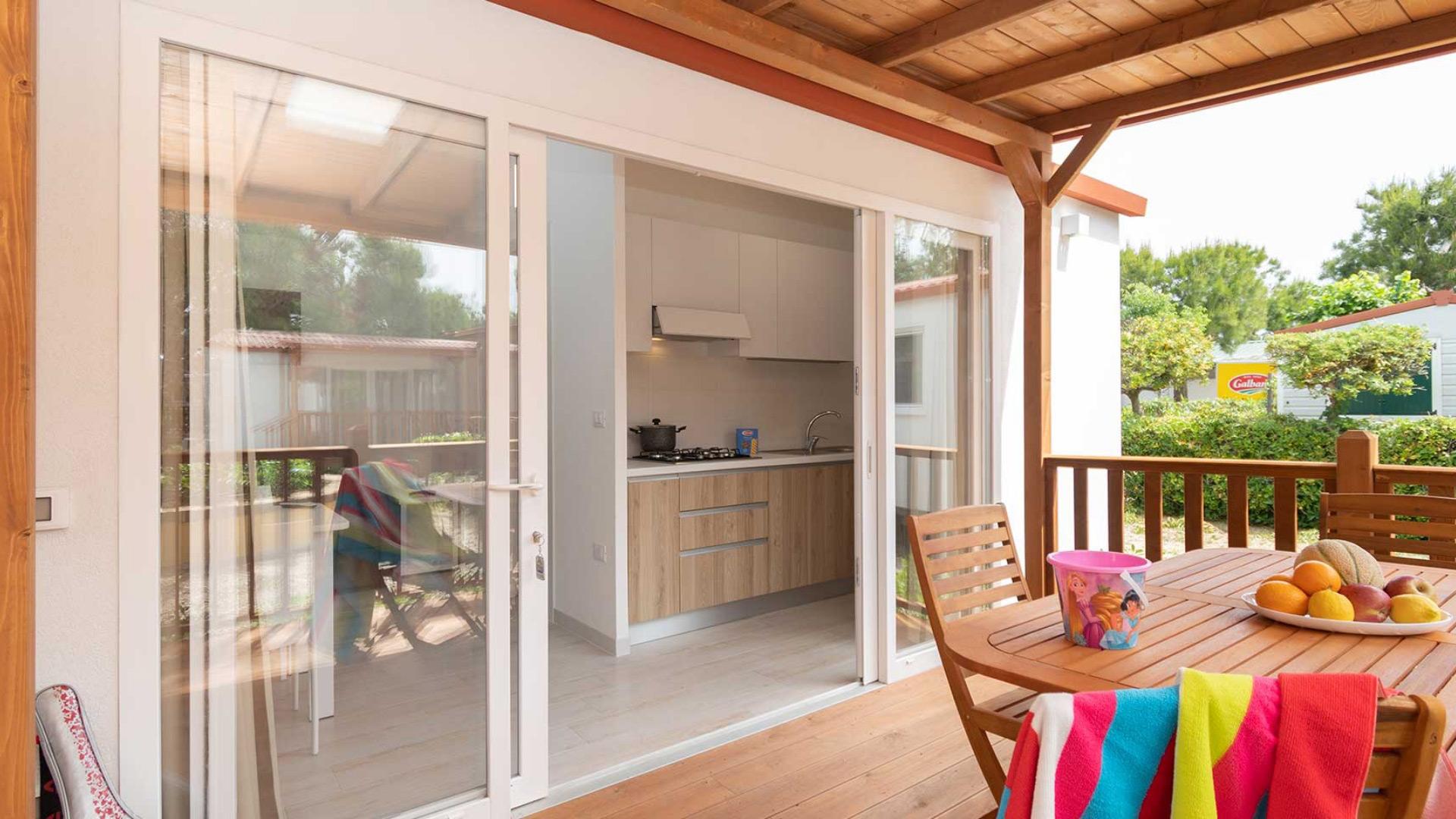 Veranda con tavolo in legno, frutta e vista cucina.