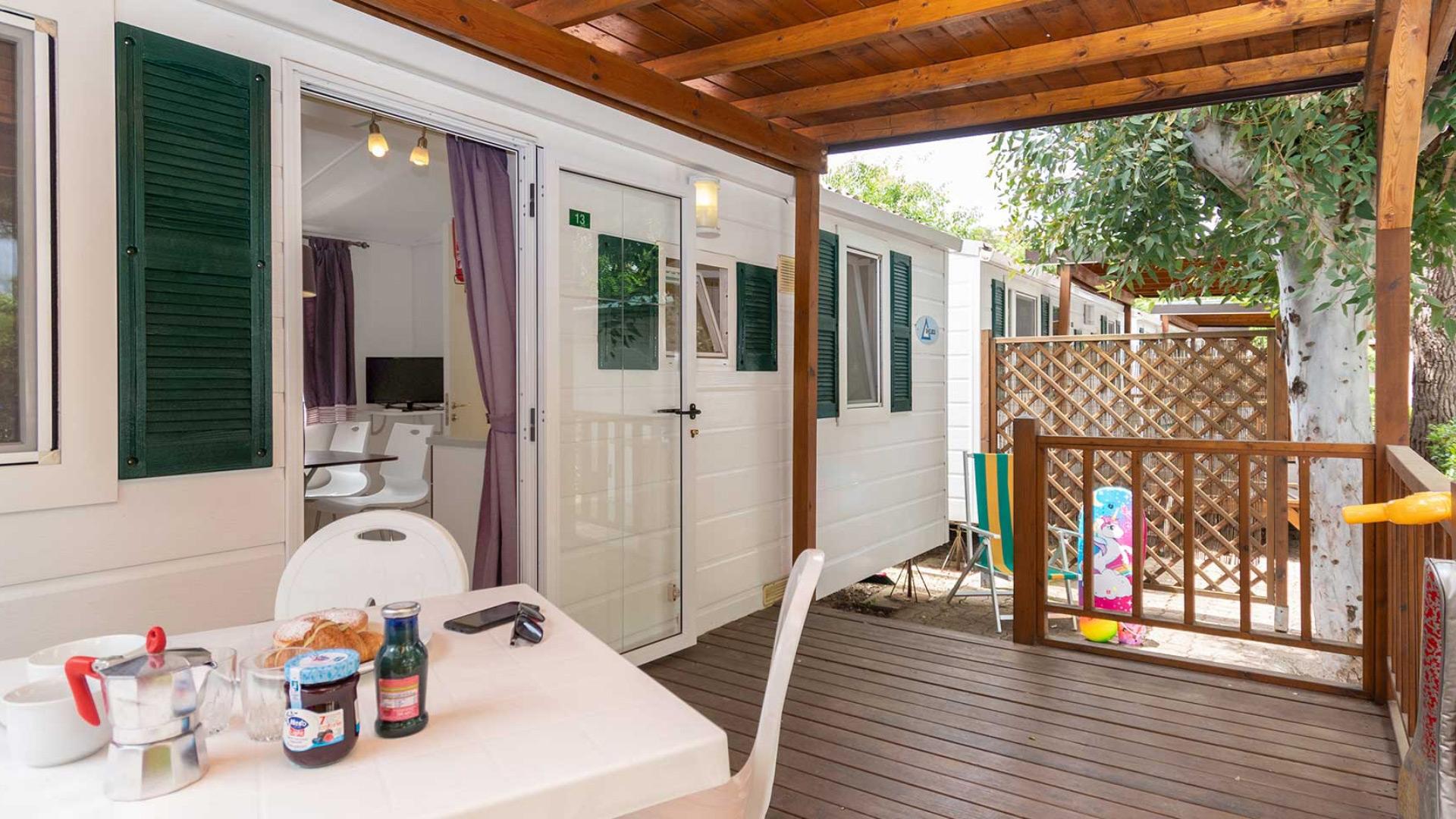 Veranda accogliente con tavolo apparecchiato, sedie e vista su un giardino.