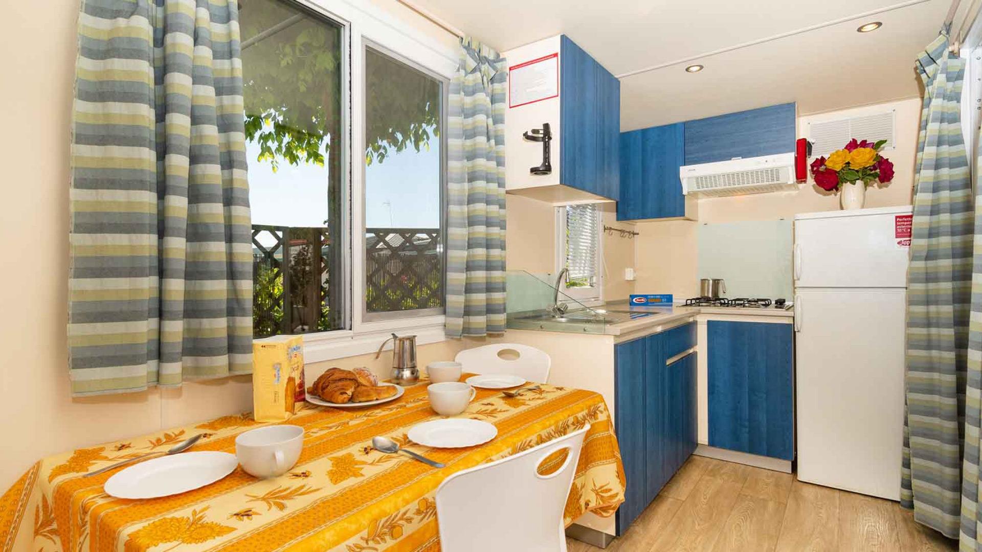 Cuisine compacte avec table dressée et meubles bleus.