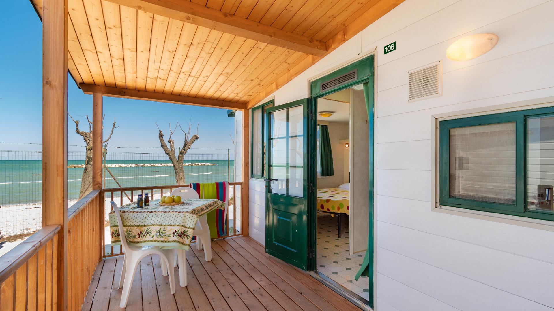 Veranda sul mare con tavolo e sedie, vista spiaggia.