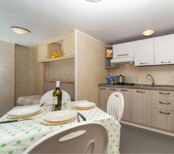 Cuisine compacte avec table dressée et réfrigérateur.