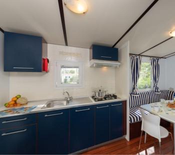 Cucina moderna con mobili blu e zona pranzo accogliente.