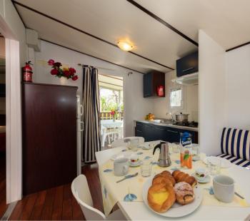 Cucina accogliente con colazione, tende a righe blu e bianche.
