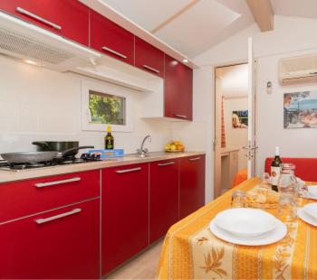 Cucina moderna con mobili rossi e tavolo apparecchiato.