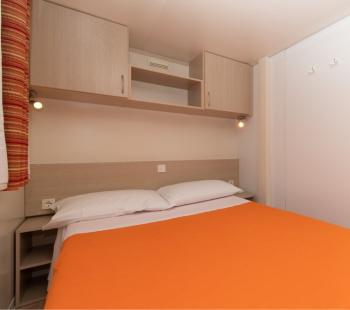 Camera da letto semplice con copriletto arancione.