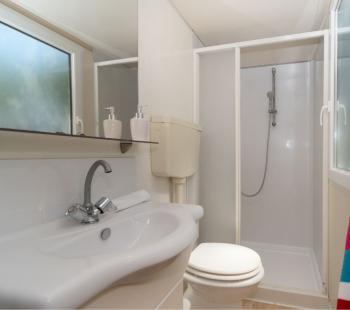 Bagno compatto con doccia, lavandino e asciugamano colorato.