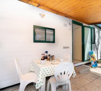 Piccola veranda con tavolo apparecchiato, sedie e skateboard.