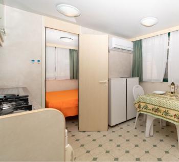Piccola cucina con tavolo apparecchiato e camera da letto.