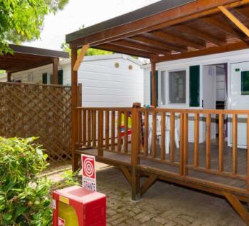 Veranda in legno di una casa mobile in campeggio, con giochi per bambini.