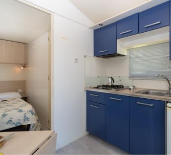 Cucina compatta con mobili blu e frigorifero Smeg.