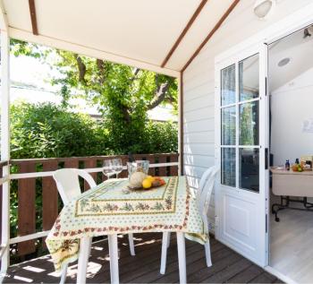 Veranda accogliente con tavolo apparecchiato, immersa nel verde.