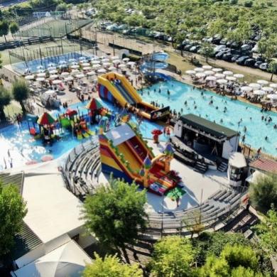 Parco acquatico con scivoli colorati e piscina affollata.