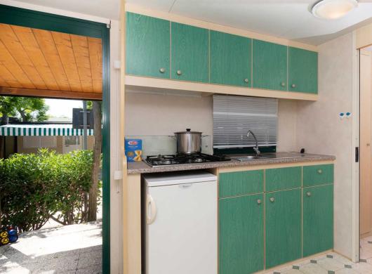 Cucina compatta con mobili verdi e vista giardino.