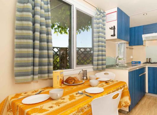 Cucina compatta con tavolo apparecchiato e mobili blu.
