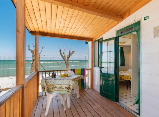 Veranda sul mare con tavolo e sedie, vista spiaggia.