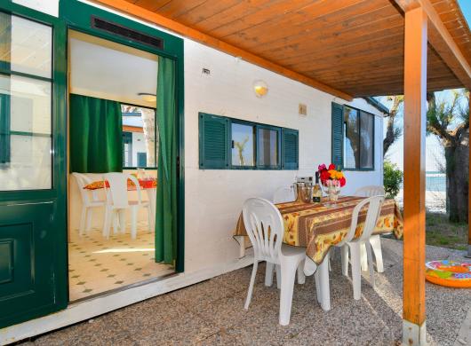 Veranda estiva con tavolo apparecchiato e vista mare.