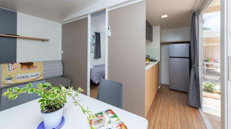 Intérieur moderne avec cuisine, salon et plante décorative.