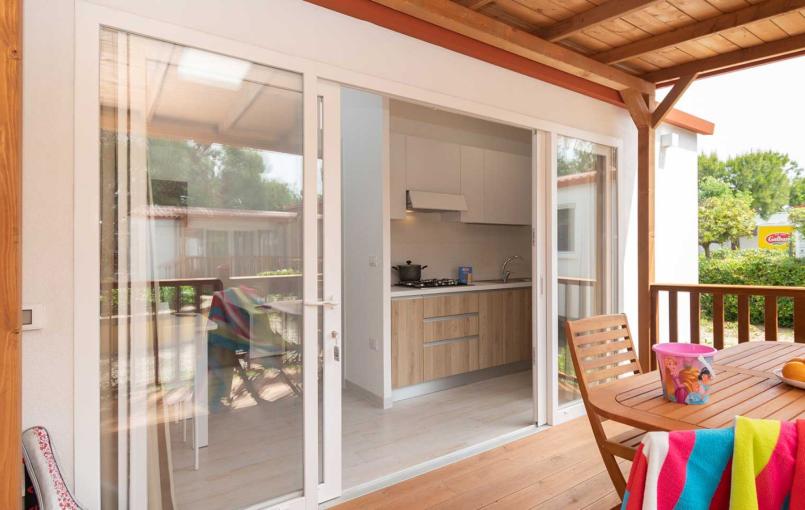 Veranda con tavolo in legno, frutta e vista cucina.