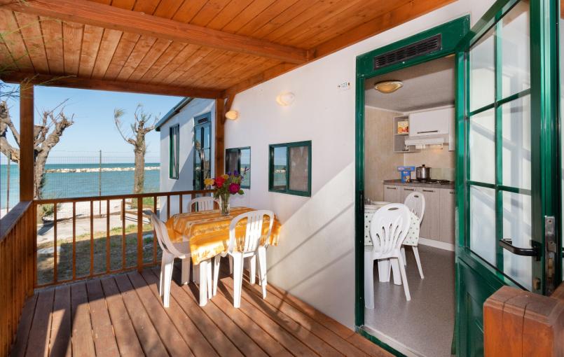 Terrazza sul mare con tavolo da pranzo e cucina interna.