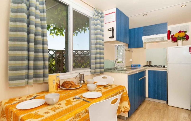 Cucina compatta con tavolo apparecchiato e mobili blu.