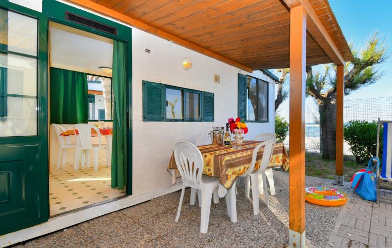 Veranda estiva con tavolo apparecchiato e vista mare.