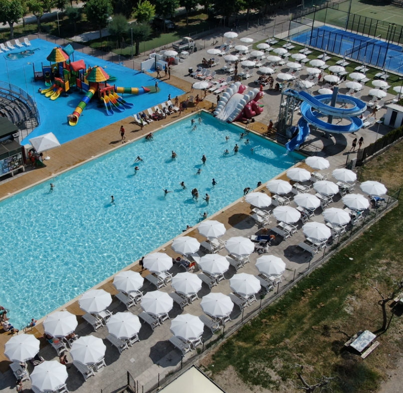 Piscina all'aperto con scivoli e area giochi per bambini.